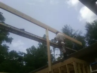 Carpenter setting a ridge beam over a new addition frame — Ice Dam Removal by Roofing Brothers in Woody Creek