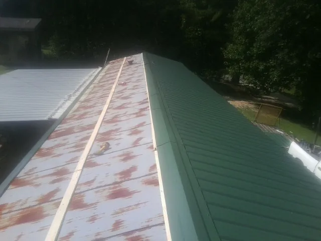 Old rusted panels beside newly installed green metal roofing — Wind Damage Roof Repair by Roofing Brothers in Woody Creek