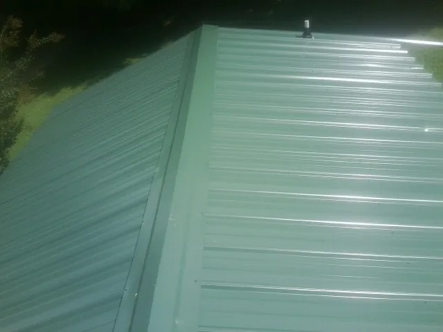 New green metal panels meeting at the ridge of a roof — Flat Roof Repair work by our crew in Woody Creek