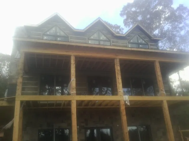 Dormers and porch framing on a large log home under construction — Roof Coating work by our crew in Woody Creek
