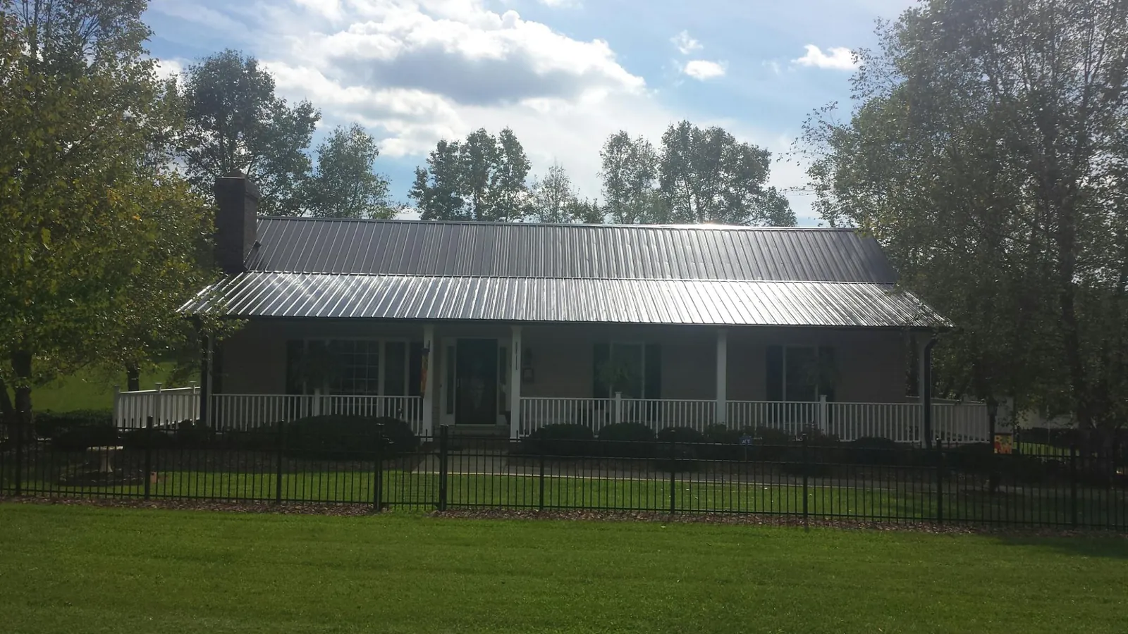 Gray metal roof on a brick ranch with a full width front porch — Gutter Guard Installation work by our crew in Woody Creek