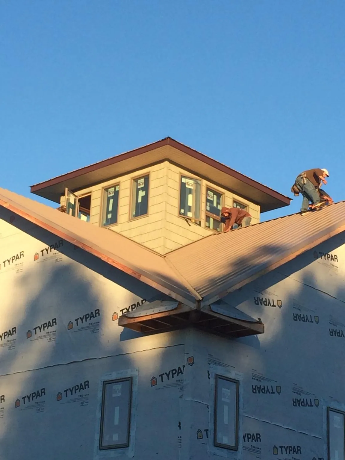 Roofers working around a rooftop cupola on a new metal roof at sunset — Roof Waterproofing in Woody Creek by Roofing Brothers